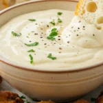 A bowl of the ultimate creamy garlic parmesan sauce, ready to be served with chicken wings.